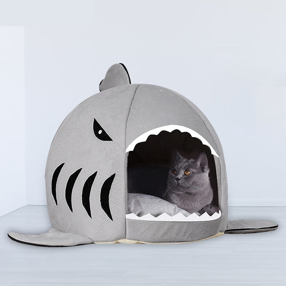 Cat sitting inside the grey shark cave bed