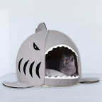 Cat sitting inside the grey shark cave bed